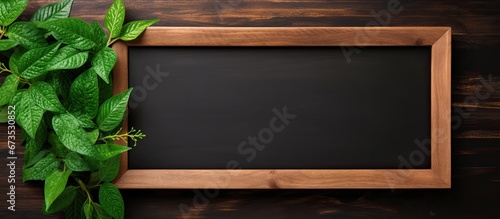 A blackboard with a wooden frame and a green plant frame following an old school design aesthetic serves as a decorative element It provides a blank space creating a mock up for various pur photo
