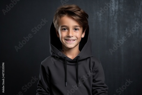 Portrait of a smiling little boy in hoodie over dark background