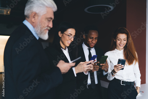 Cheerful multiethnic colleagues using smartphones in office