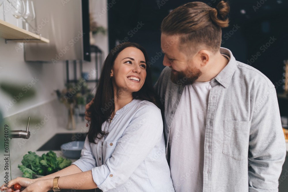 Positive guy spending time with wife in kitchen