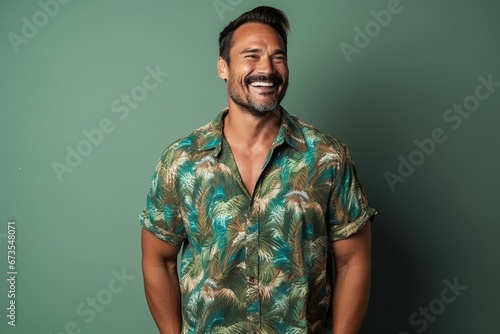 Portrait of a handsome young man laughing against a green background.