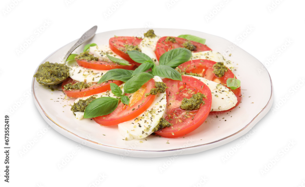 Plate of delicious Caprese salad and spoon with pesto sauce isolated on white Plate of delicious Caprese salad and spoon with pesto sauce isolated on white