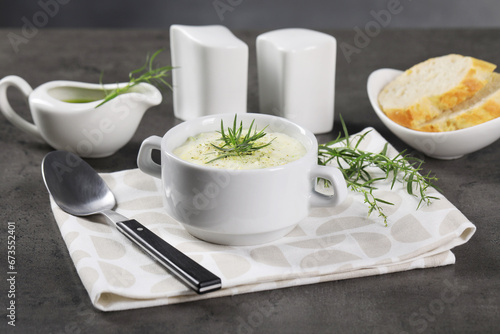 Delicious cream soup with tarragon, spices and potato in bowl served on dark textured table
