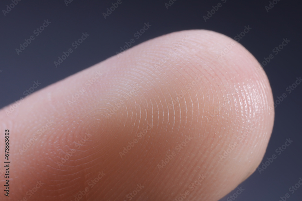 Finger with friction ridges on dark background, macro view Finger with friction ridges on dark background, macro view