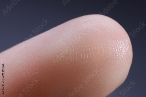 Finger with friction ridges on dark background, macro view