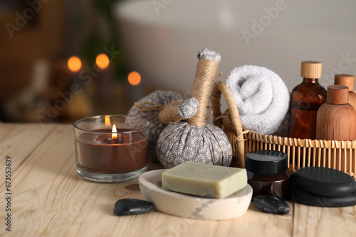 Composition with spa products and burning candle on wooden table in bathroom, closeup. Space for text