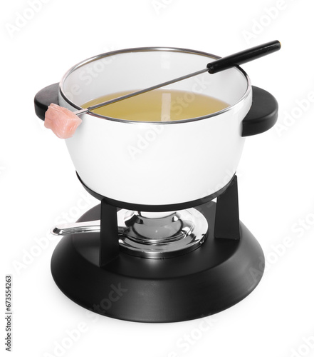 Oil in fondue pot and fork with piece of raw meat isolated on white