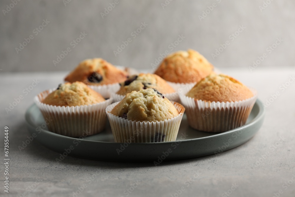 Delicious sweet muffins with berries on grey table Delicious sweet muffins with berries on grey table