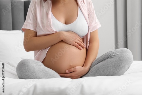 Pregnant woman on bed at home, closeup