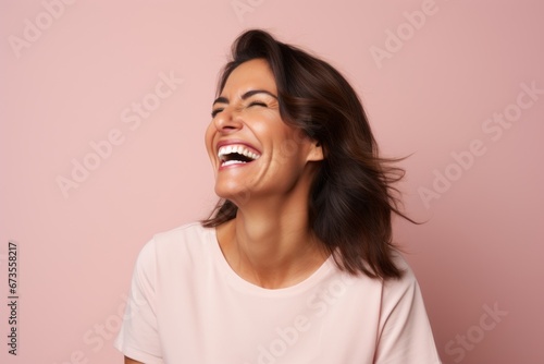 Happy young woman laughing and looking up at copyspace over pink background