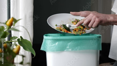 Food loss in household. A lot of food is wasted. Man throws half-eaten meal leftovers in the trash can photo