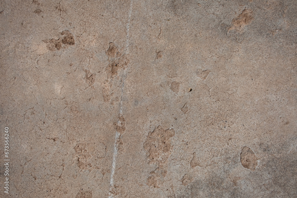 Detail of a deteriorating concrete floor with cracks and pock marks. The concrete has a brown-beige color with hints of grey. Detail of a deteriorating concrete floor with cracks and pock marks. The concrete has a brown-beige color with hints of grey.