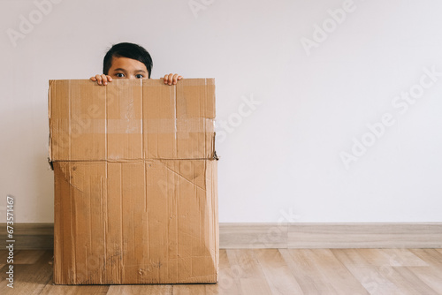 Little Asian boy hiding inside cardboard box photo