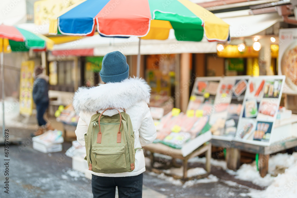 Woman tourist Visiting in Hakodate, Traveler in Sweater sightseeing Asaichi Morning Market Hakodate in winter. landmark and popular for attractions in Hokkaido, Japan. Travel and Vacation concept