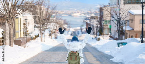 Woman tourist Visiting in Hakodate, Traveler in Sweater sightseeing Hachiman Zaka Slope with Snow in winter. landmark and popular for attractions in Hokkaido, Japan. Travel and Vacation concept photo