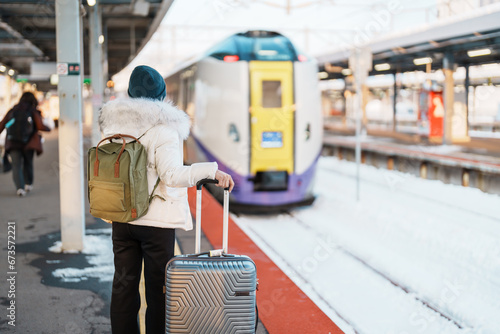 Woman tourist with bag in Train Station platform with Snow in winter. Hakodate, Hokkaido, Japan.Travel and Vacation concept