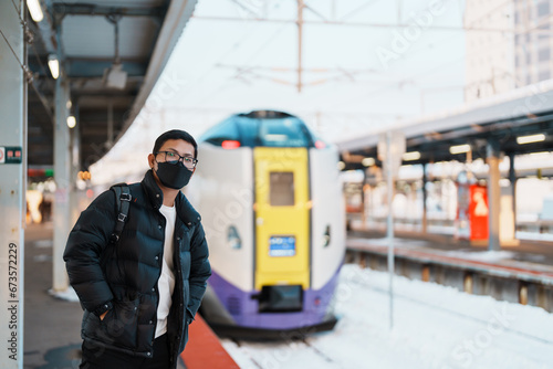 man tourist with bag in Train Station platform with Snow in winter. Hakodate, Hokkaido, Japan.Travel and Vacation concept