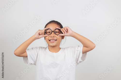 cute little preschooler girl isolated on grey studio background wear glasses look at camera  small child try spectacles at opticians  kid eyesight correction treatment concept