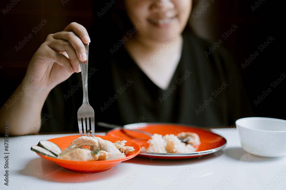 Young Asian girl is forking a piece of chicken with smile face expression bokeh background Young Asian girl is forking a piece of chicken with smile face expression bokeh background