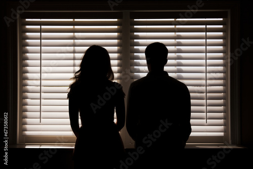 Silhouette of a couple facing a window with blinds