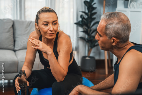 Athletic and sporty senior couple portrait in sportswear sitting on sofa as home exercise concept. Healthy fit body lifestyle after retirement. Clout