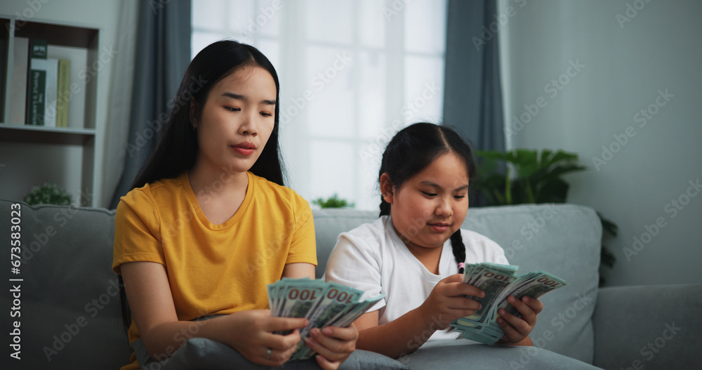 Portrait of young women and teen girl counting cash money on sofa in the living room at home,Happy counting dollars banknote. Portrait of young women and teen girl counting cash money on sofa in the living room at home,Happy counting dollars banknote.