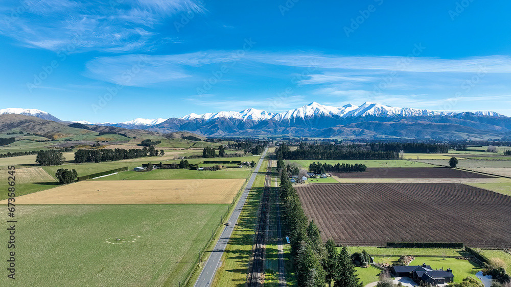 Aerial farming grazing and crop fields in rural countryside with a backdrop of the snow capped Mountain range under clear skies Aerial farming grazing and crop fields in rural countryside with a backdrop of the snow capped Mountain range under clear skies