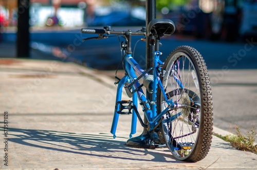The back view of bicycle is locked at the pole on the sidewalk. The front wheel was stolen from the thief.