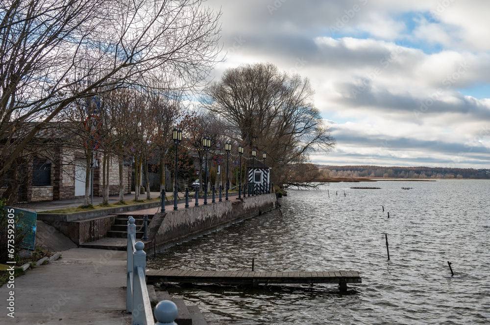 Small embankment with pier for boats and on the lake bank. Small street of the province town.