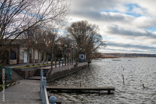 Small embankment with pier for boats and on the lake bank. Small street of the province town.