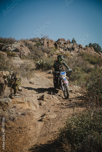 Female dirt biker on desert trail in Prescott Arizona with cactus and rock outcroppings