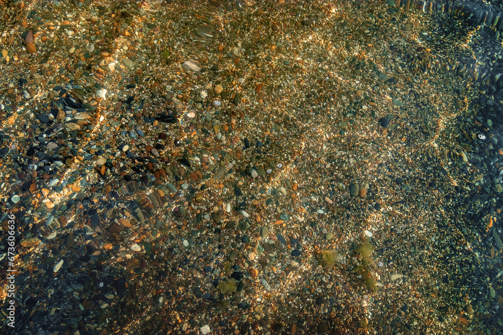 View of the seabed near the shore through clear water. Patterns of the sun breaking through crystal clear water on the seabed. Perfectly clean sea water and the seabed near the shore. 