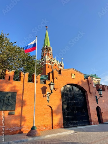 Troitskaya (Trinity) Tower, Moscow city, Kremlin, capital of Russia. Arched antique metal gate, icon of Savior above. Flag of Russian Federation on flagpole flutters in wind. Kremlin wall, red brick
