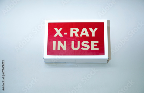 Vintage box shaped sign on a wall stating X-Ray In Use with white letters on a red background