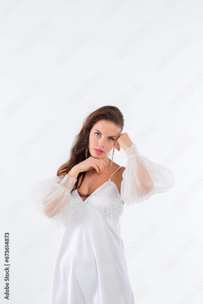 A young girl in a beautiful white dress in a white photo studio.