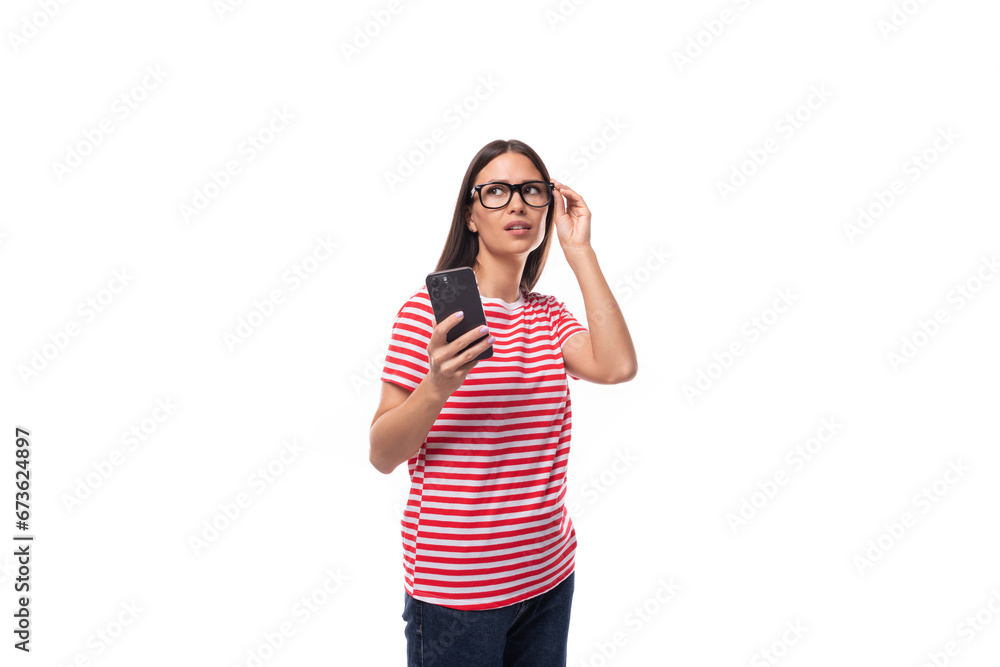 charming young caucasian woman with straight hair with glasses and in a striped t-shirt holds a smartphone in her hand. people lifestyle concept charming young caucasian woman with straight hair with glasses and in a striped t-shirt holds a smartphone in her hand. people lifestyle concept