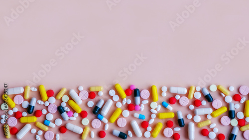 Pills and capsules with medicines on a pink background, there is space for copy. © DNV
