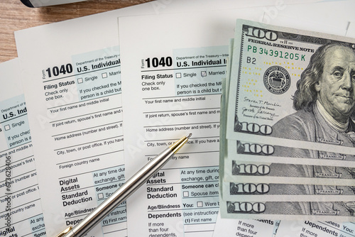 Dollar bills and pen lying on the 1040 form. The concept of filing a tax return