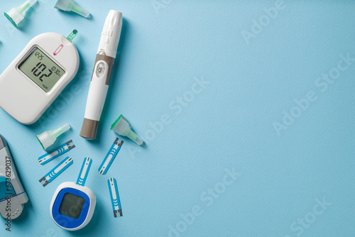 Top view of glucometer, lancet pen and strips on blue background. diabetes test kit