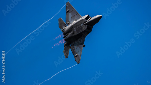 U.S. Air Force F-22 Raptor overhead pass with afterburners and wing-tip vortices  