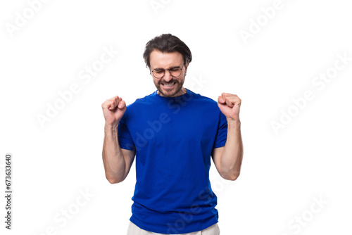 young brunette European man with a well-groomed beard in a blue T-shirt hopes for the best