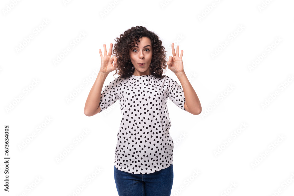 young surprised well-groomed brunette curly woman dressed in a polka dot print blouse young surprised well-groomed brunette curly woman dressed in a polka dot print blouse