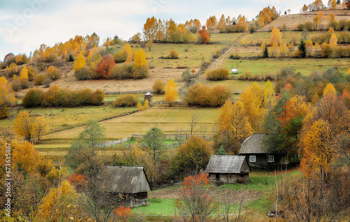 Autumn in the Carpathians. Yellow trees and houses on the mountainside.
