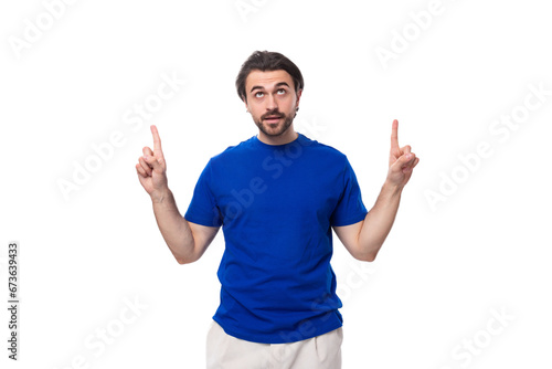 young brutal caucasian brunette man with a beard in a blue t-shirt keeps the secret of business development on a white background with copy space
