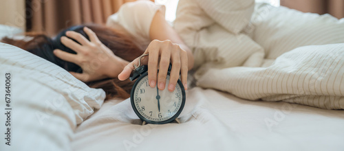 Fotografie alarm clock and asian woman hand stop time in bed while sleeping, young adult female wake up late in the early morning