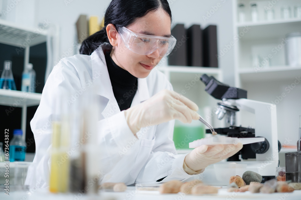 A female geologist or archaeologist is analyzing and focusing on a sample of rock or mineral in paleontology, archaeological and geological or mining laboratory. Concept of fossil or ground research. A female geologist or archaeologist is analyzing and focusing on a sample of rock or mineral in paleontology, archaeological and geological or mining laboratory. Concept of fossil or ground research.