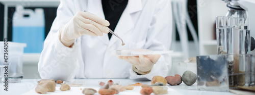 Close up of geologist or archaeologist is picking and focusing on a sample of rock, stone or mineral in paleontology, archaeological and geological or mining laboratory. Concept of ground research. photo