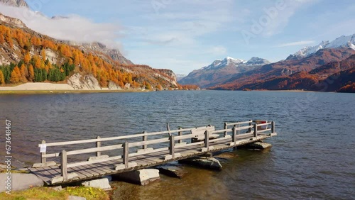 4k drone forward video (Ultra High Definition) of wooden pier on Sils Lake (Silsersee). Amazing autumn scene of Swiss Alps, Maloja Region, Upper Engadine, Switzerpand, Europe.. photo