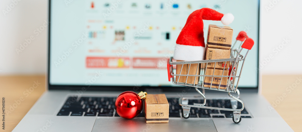 Christmas Online Shopping concept. Boxes with shopping cart on a laptop computer. Sale and discount during Christmas and New Year holiday, ecommerce, shipping delivery, logistics and Cyber Monday