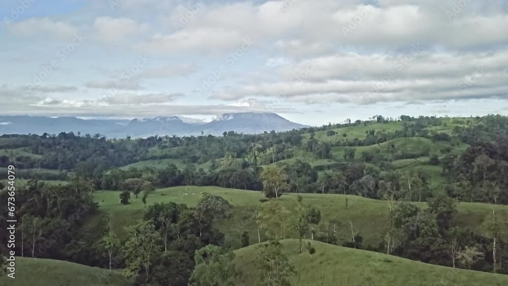 Aerial view rising up over the green hills and tropical jungle to Arenal Volcano in Cano Negro Wildlife Refuge, Costa Rica with cumulus clouds in background. Aerial view rising up over the green hills and tropical jungle to Arenal Volcano in Cano Negro Wildlife Refuge, Costa Rica with cumulus clouds in background.